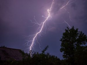 Lightning Striking The Ground Against A Dark Sky.